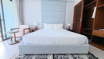 Una habitación de hotel moderna con una cama grande, una zona de estar con una mesa y un armario.