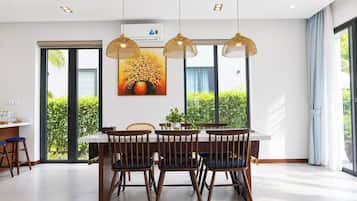Un comedor moderno con una mesa, sillas, luces colgantes y un ventanal con vistas a zonas verdes.