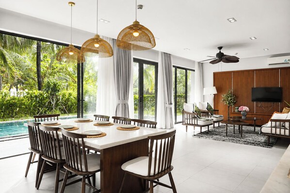 A modern dining area with a large table, chairs, and pendant lighting.