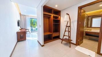 A hotel room with a wooden wardrobe, a desk, a lamp, and a bathroom visible through an open door.