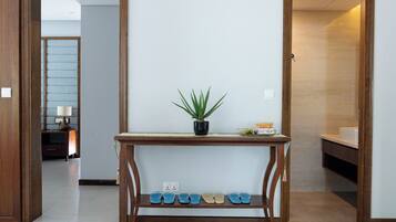 A hallway with a wooden console table, a potted plant, and a shoe rack.