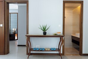 A hallway with a wooden console table, a potted plant, and a shoe rack.