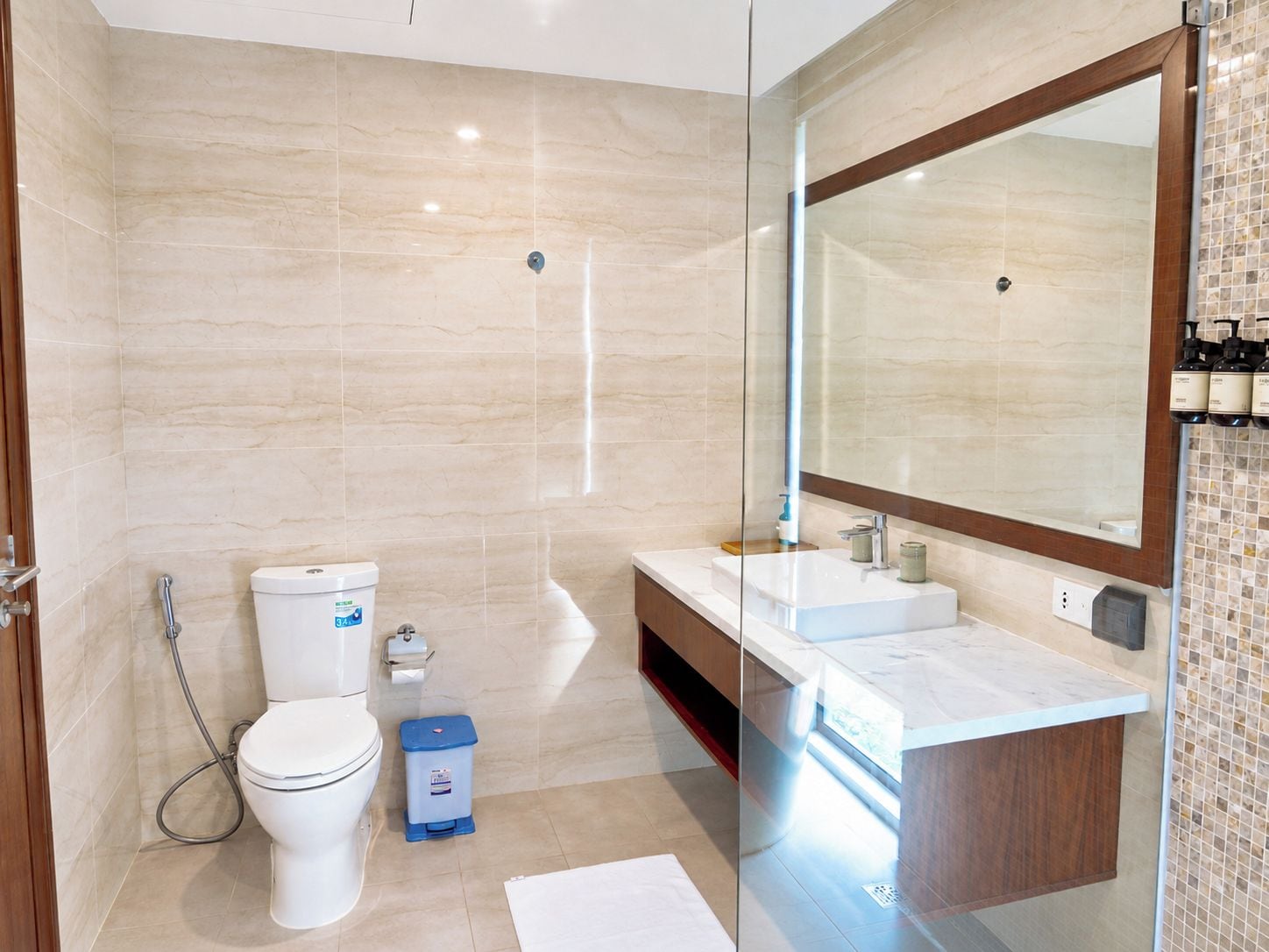 Une salle de bain moderne équipée de toilettes, d’un bidet et d’une douche séparée par des parois en verre.
