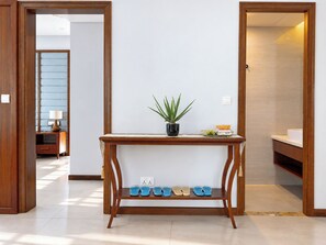 A hallway with a wooden console table, a potted plant, and a shoe rack with sandals. - Sonasea Villas Collection Long Beach Phu Quoc (Phu Quoc)