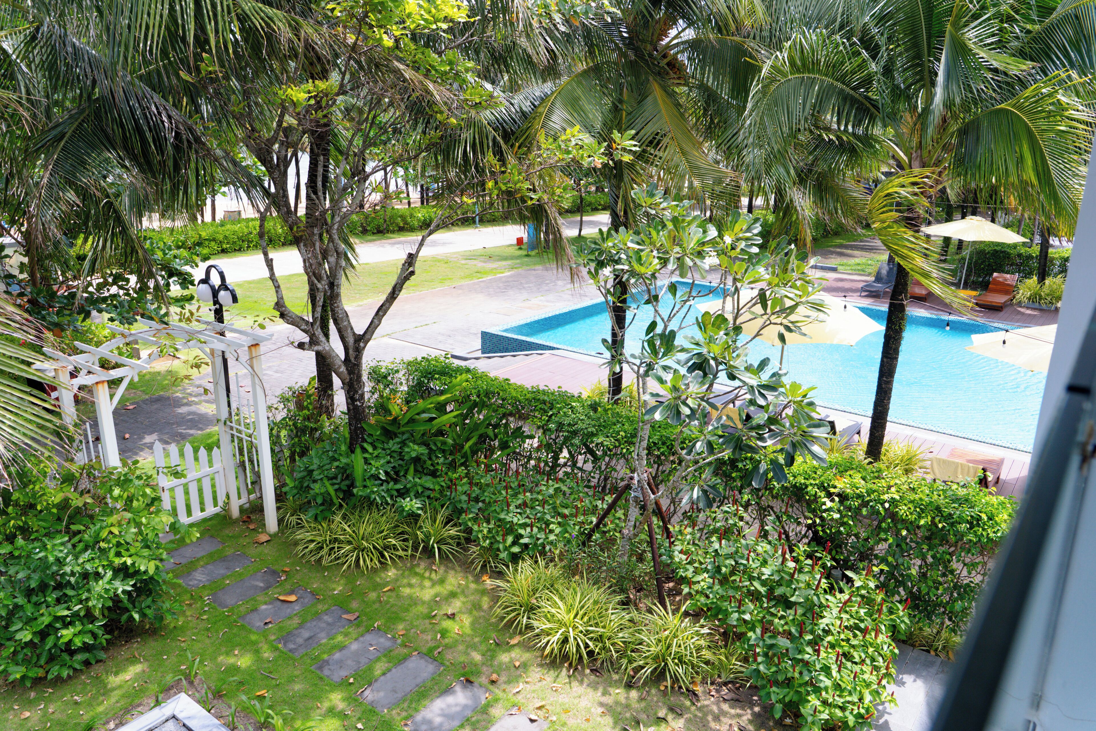 Una piscina rodeada de exuberante vegetación y una cerca blanca.