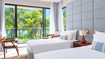 Een hotelkamer met twee bedden, een bureau en uitzicht op palmbomen.