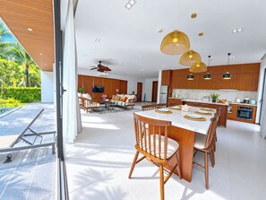 A modern kitchen with wooden cabinets, a central island, and pendant lighting. - Sonasea Villas Collection Long Beach Phu Quoc (Phu Quoc)