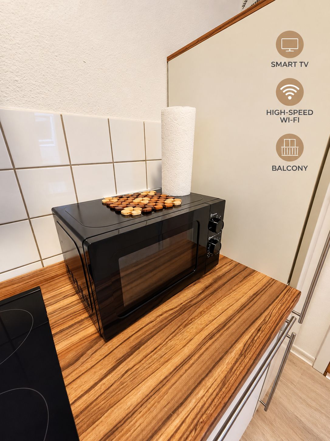 Een moderne keuken met een zwarte magnetron, een houten aanrecht en een witte betegelde spatwand.