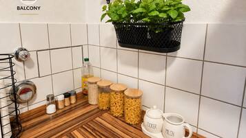 Une cuisine avec un plan de travail en bois, un pot à suspendre pour plantes et une tasse blanche sur laquelle est inscrit « ZUCKER MILK ».