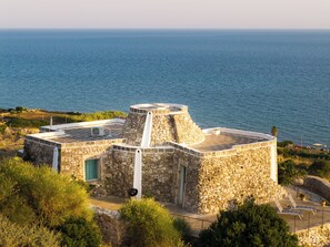 A stone building with a circular tower, a door, and a small balcony. - TRULLO EXCLUSIVE (Torre Vado)