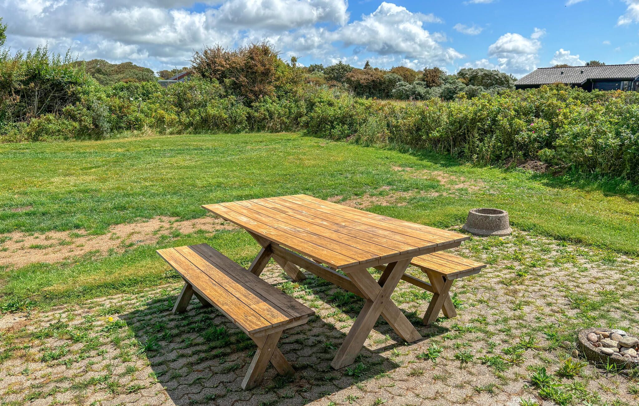 Un tavolo da picnic in legno con panche in una zona erbosa all'aperto.
