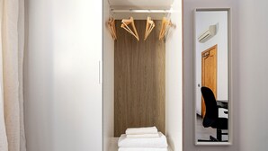 A bathroom with a wooden vanity, a mirror, a towel rack, and a black chair. - Design and Comfort in Prosperity (Madrid)
