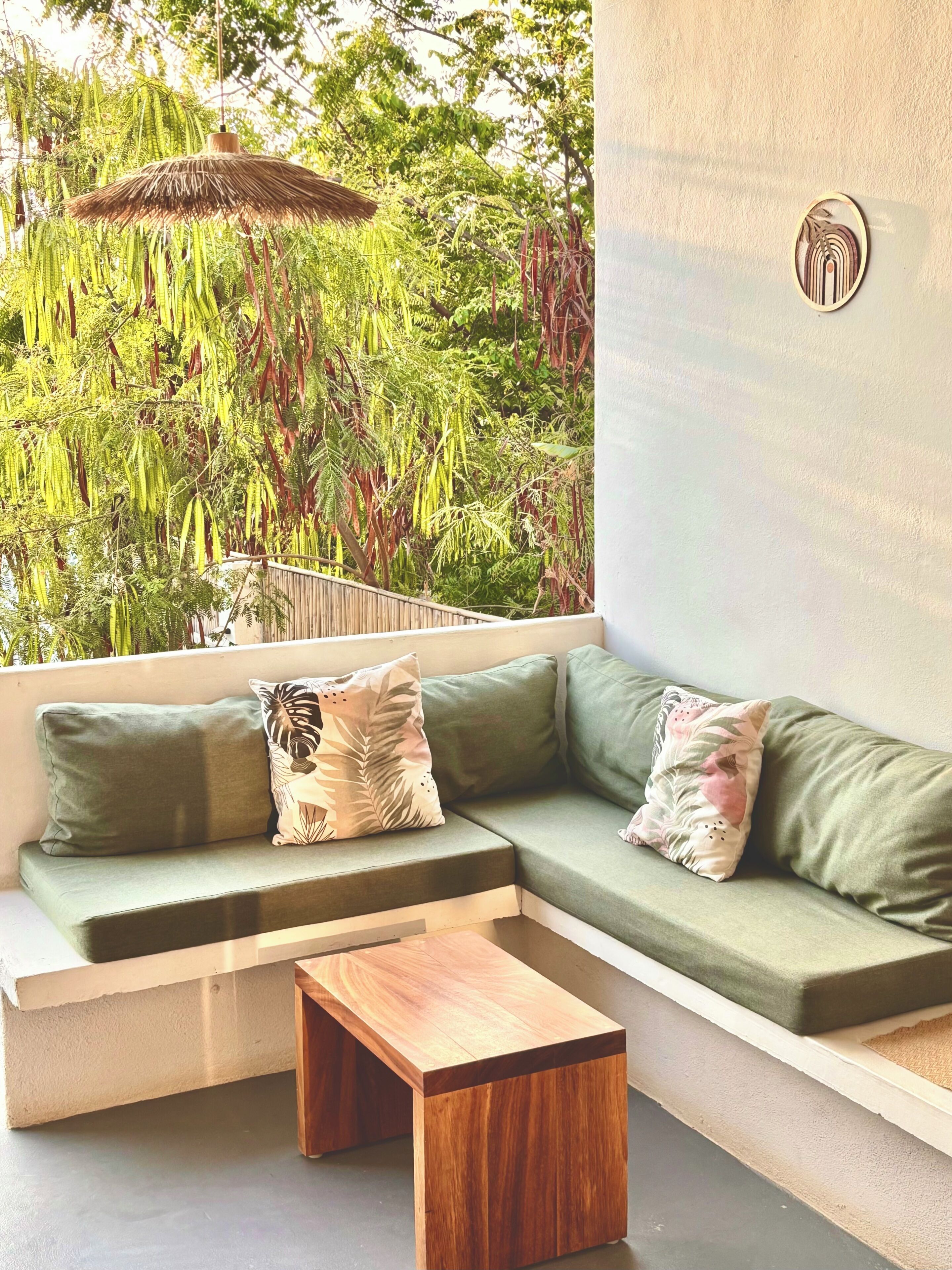 A modern outdoor seating area with a wooden coffee table, green cushioned sofa, and decorative pillows.