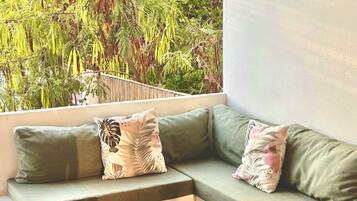 A modern outdoor seating area with a wooden coffee table, green cushioned sofa, and decorative pillows.