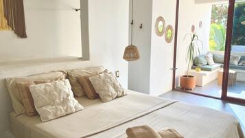 A bedroom with a large bed, a view of the outdoor seating area, and a hanging light fixture.