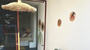 A modern living room with a sofa, a hanging light fixture, and a potted plant. - Kasa Koh  (Brisas de Zicatela)
