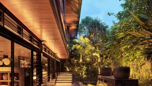 A modern building with a wooden deck, outdoor seating, and a water feature.