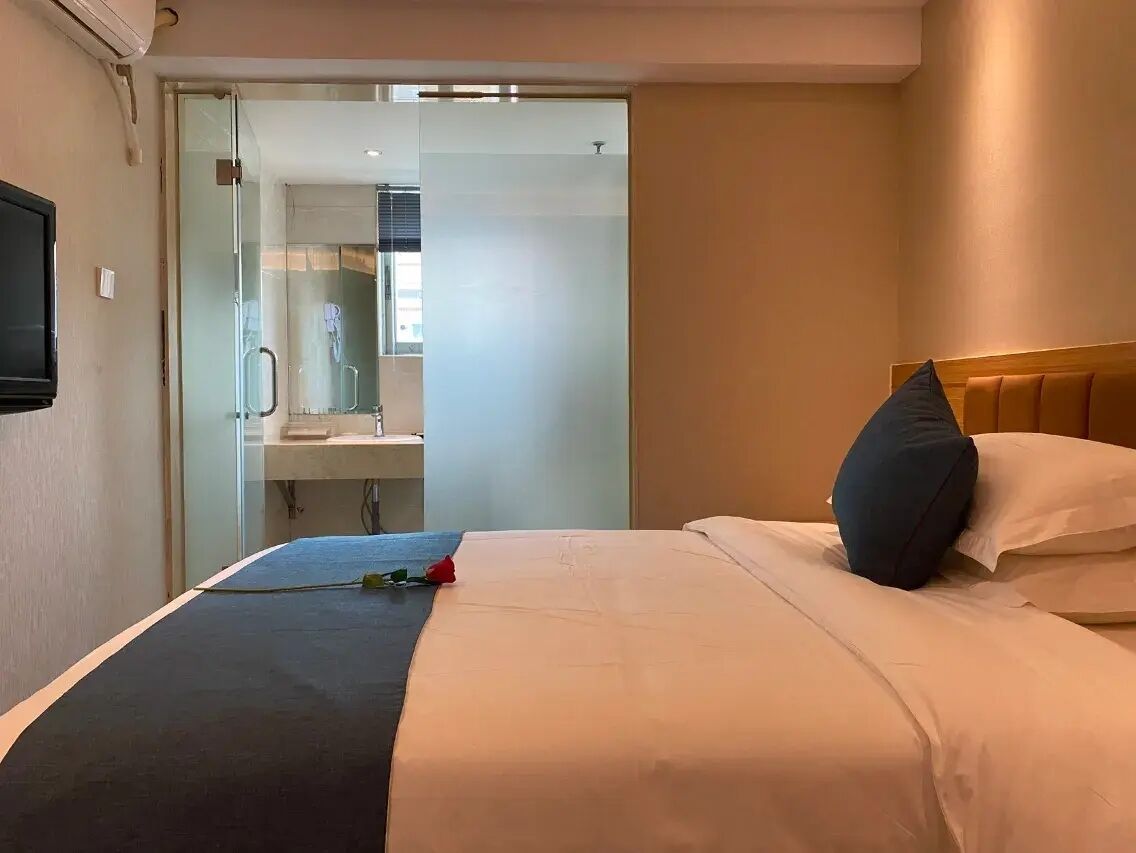 Ein Hotelzimmer mit Bett, Fernseher, Bad mit Spiegel und Dusche.
