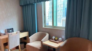A room with two armchairs, a small table, a desk with a chair, and a window with curtains.