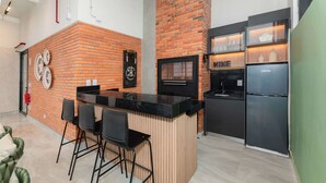 A kitchen with a brick wall, a black countertop, and a stainless steel refrigerator. - Corporate Stays Matrisa - 405 (Asunción)