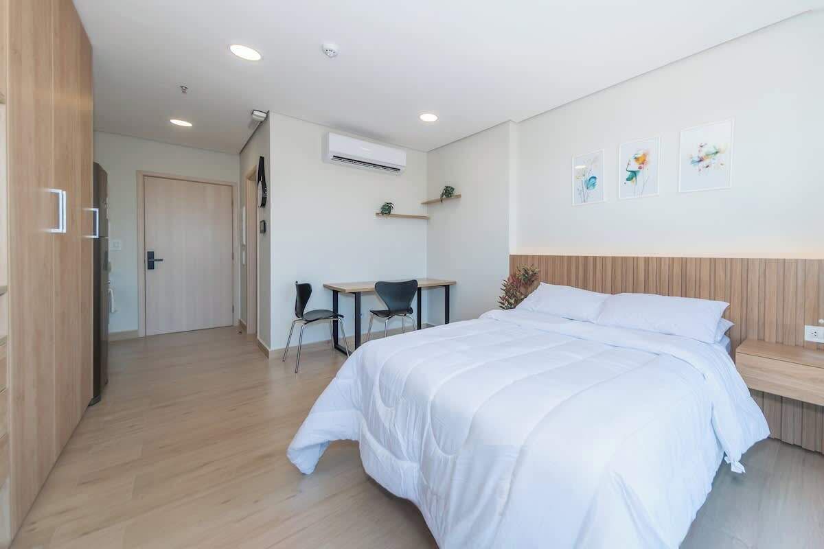 A modern hotel room with a large bed, a desk, and a chair.