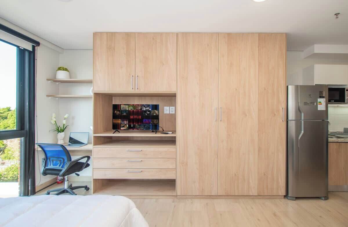 A modern kitchen with a built-in refrigerator, wooden cabinets, and a window overlooking greenery.