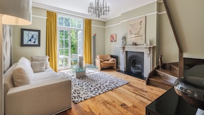 A living room with a sofa, glass coffee table, and a fireplace. - The Mid-Century Modern Maisonette, by Veeve (London)