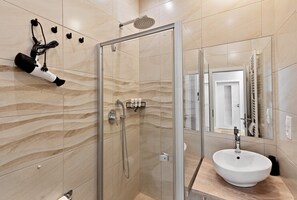 Un bagno con doccia vetrata, un lavandino bianco e un portasciugamani.