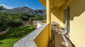 A balcony with a stone ledge, a table with chairs, a book, and a mountain view. - Cozy apartment in Starigrad Paklenica with WiFi (Starigrad Paklenica)