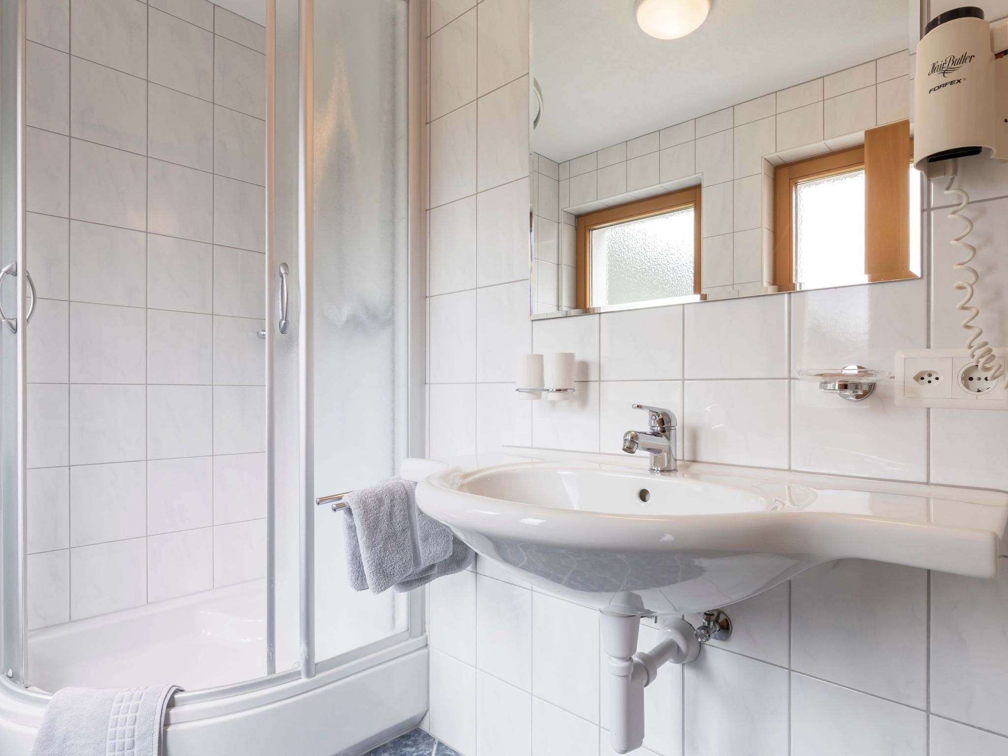 Ein modernes Badezimmer mit Dusche, Waschbecken und Spiegel.