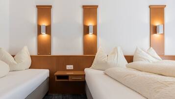 Una habitación de hotel con dos camas, una mesita de noche e iluminación instalada en la pared.