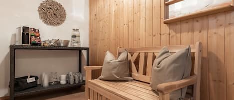 A wooden bench with cushions, a shelf with various items, and a wall-mounted picture.