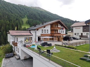 Un bâtiment à deux étages doté d’un balcon, d’un espace extérieur aménagé pour s’asseoir et d’une piscine.