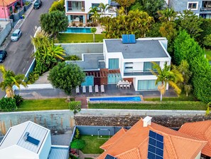 Een modern huis met een zwembad, zonnepanelen en een keurig onderhouden tuin.
