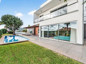 A modern house with a swimming pool, a patio with lounge chairs, and a large glass door leading to a living area. - Al Mirase by Interhome (Funchal (Madeira))