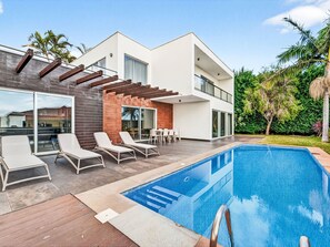 Een moderne twee-onder-een-kapwoning met zwembad, terras en een patio.