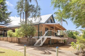 A two-story house with a wooden deck, a staircase, and a fenced yard. - Riverscape Cottage No.12 with river views - Riverscape  - unit 12 with river views (Augusta)