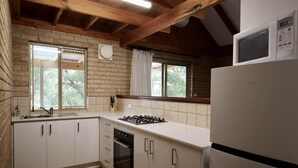 Uma cozinha compacta com armários brancos, fogão a gás, forno embutido e geladeira.