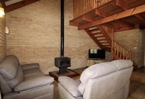 Ein Wohnzimmer mit zwei Ledersofas, einem Fernseher und einem Kaminofen.