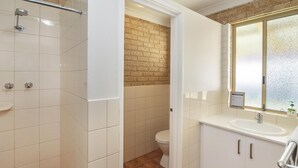 Et badeværelse med bruser, toilet og håndvask.