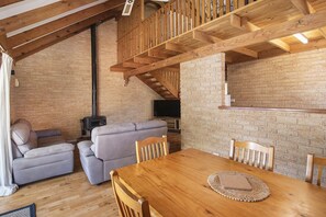 Ein gemütlicher Wohnbereich mit Kamin, Sofas, einem Holztisch und einem Fernseher.
