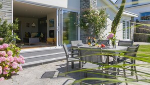 Een modern huis met een terras, tuinmeubels en een eettafel voor vier personen.