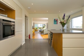 A modern kitchen with a built-in oven, a wooden countertop, and a view into a dining area. - Secret Beach, Carbis Bay – Sleeps 6 – Sea Views – Dog-Friendly – On-Site Parking (Carbis Bay)