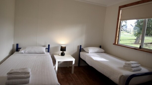 Een kamer met twee éénpersoonsbedden, een tafeltje met een lamp en een raam met uitzicht op het omliggende landschap.