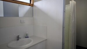 Ein Badezimmer mit einem weißen Waschbecken, Spiegel und einer Duschvorhang.