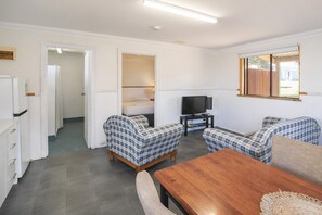 A room with a wooden table, two plaid sofas, a television, and a mirror.