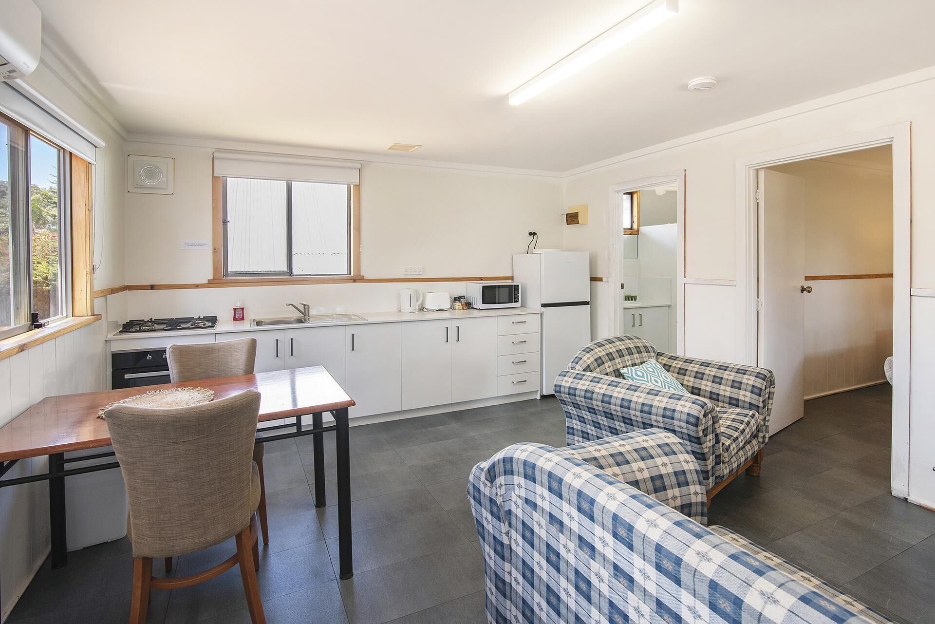 Une cuisine compacte comprenant une table à manger, des chaises et un coin cuisine.