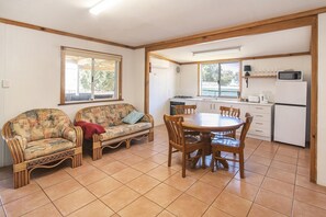 A cozy room with a sofa, a dining table, and a kitchen area. - Riverscape Cottage No.5 - Riverscape - Cottage 5 (Augusta)