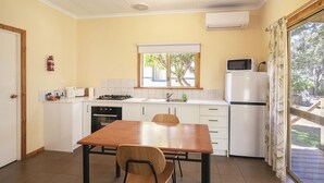 A compact kitchen with a dining table, chairs, a stove, a sink, and a refrigerator. - Riverscape Cottage No.8 with River Views - Riverscape - unit 8 with views over the Blackwood River (Augusta)