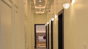 A hotel hallway with a polished marble floor, recessed ceiling lights, and a fire extinguisher. - GS Palace Ayodhya (Ayodhya)